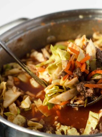 pot of venison cabbage roll soup with a hand pulling out a ladle full