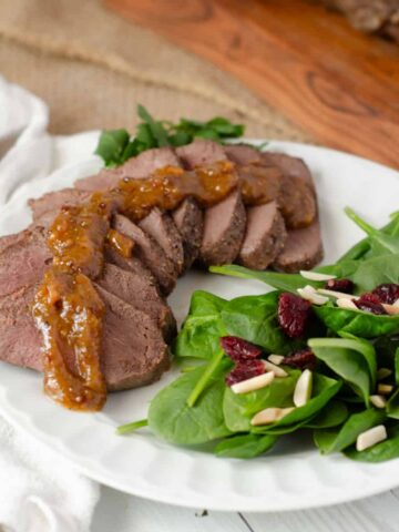 air fryer venison backstrap sliced and plated with a salad and garnishes