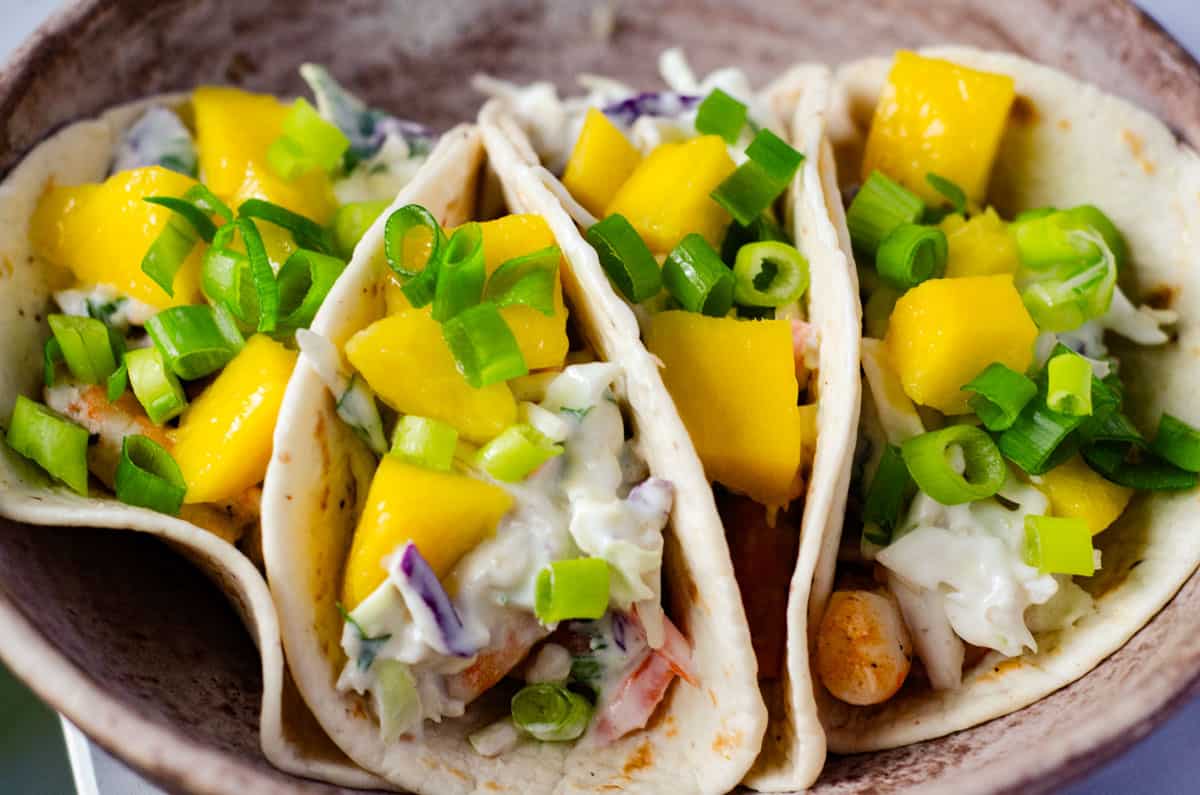 close up view of the end of shrimp tacos packed in a bowl
